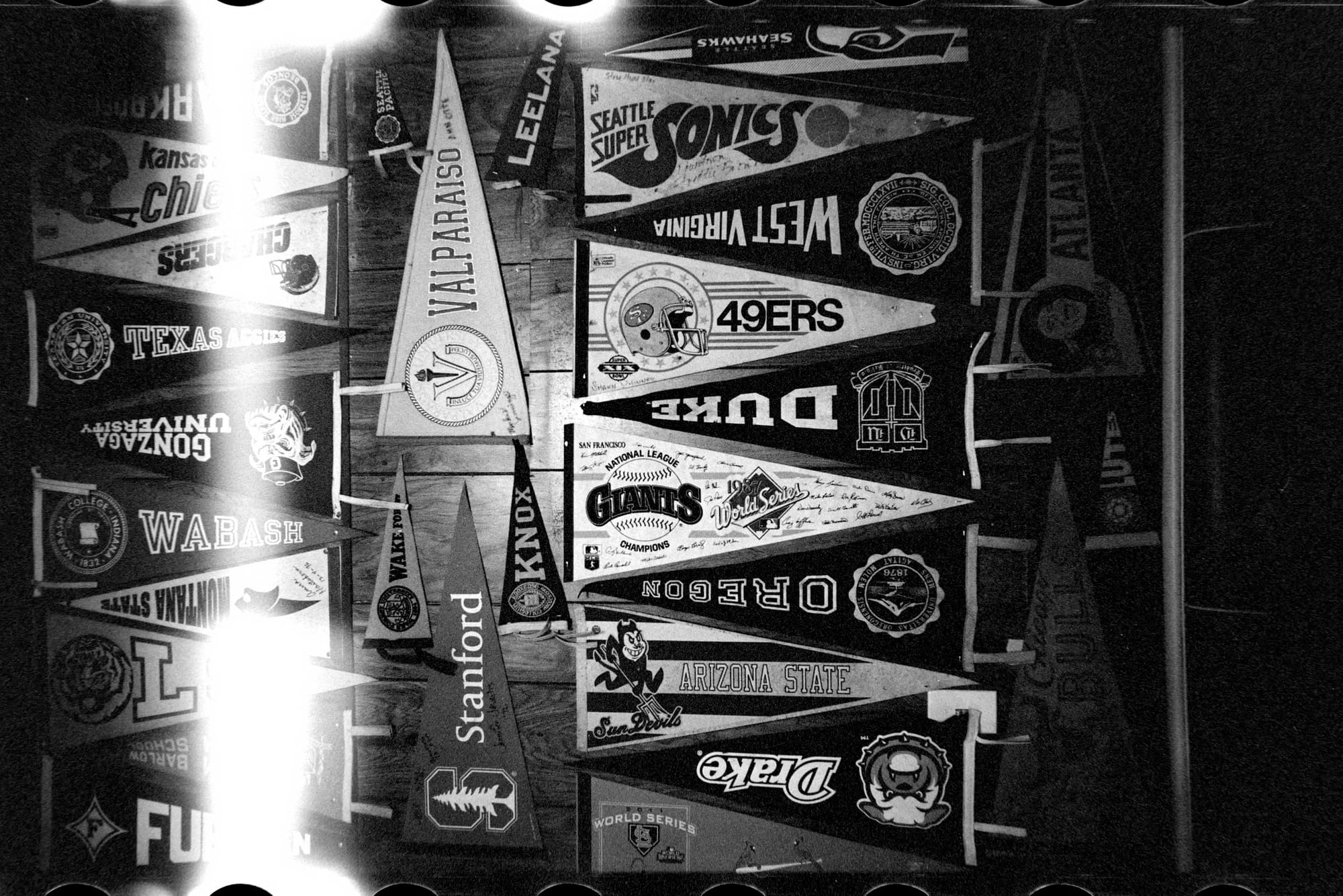 black and white photo of many triangle shaped pennants for a variety of sports teams.