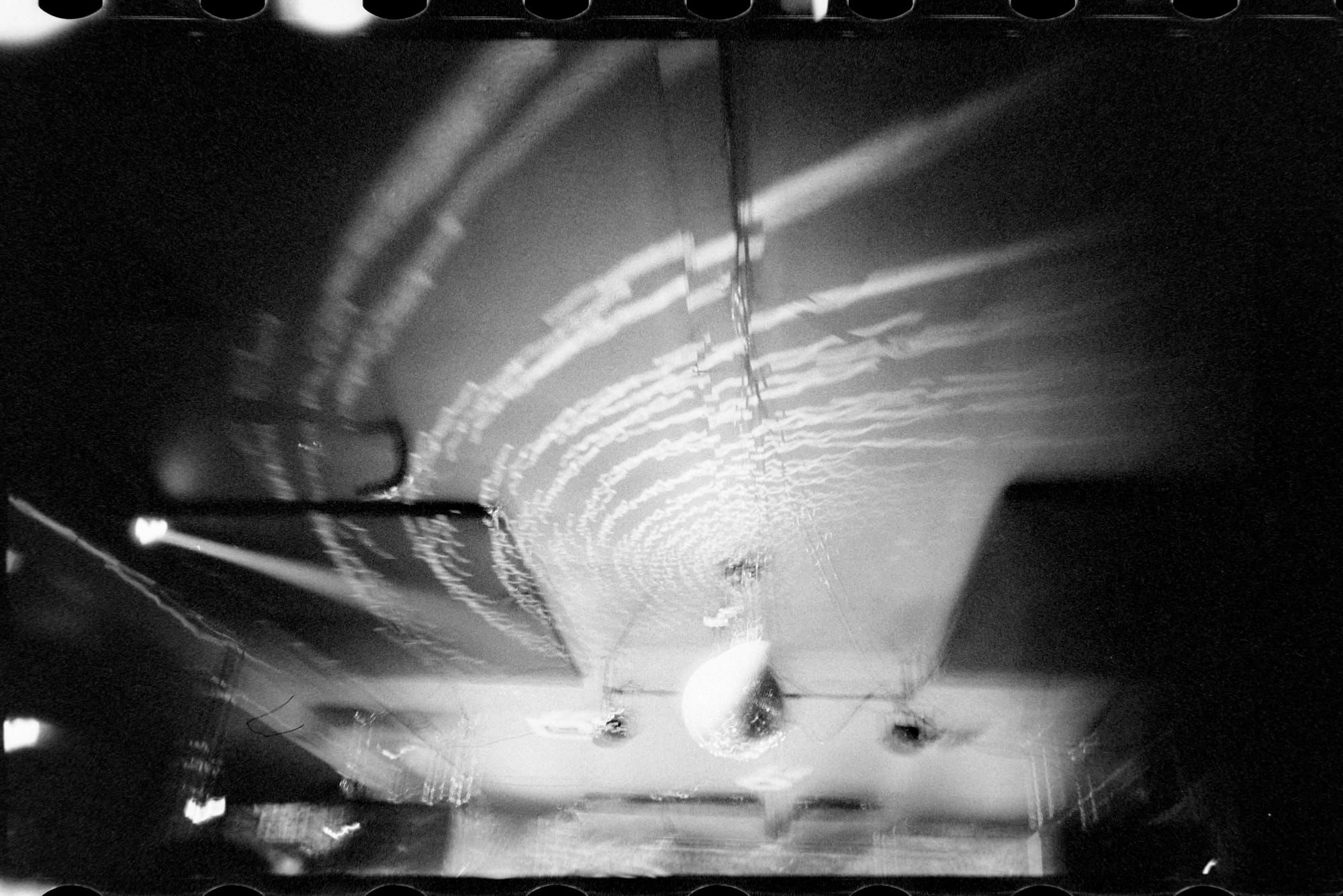 A disco ball on a ceiling making a spiral of blurry lights.