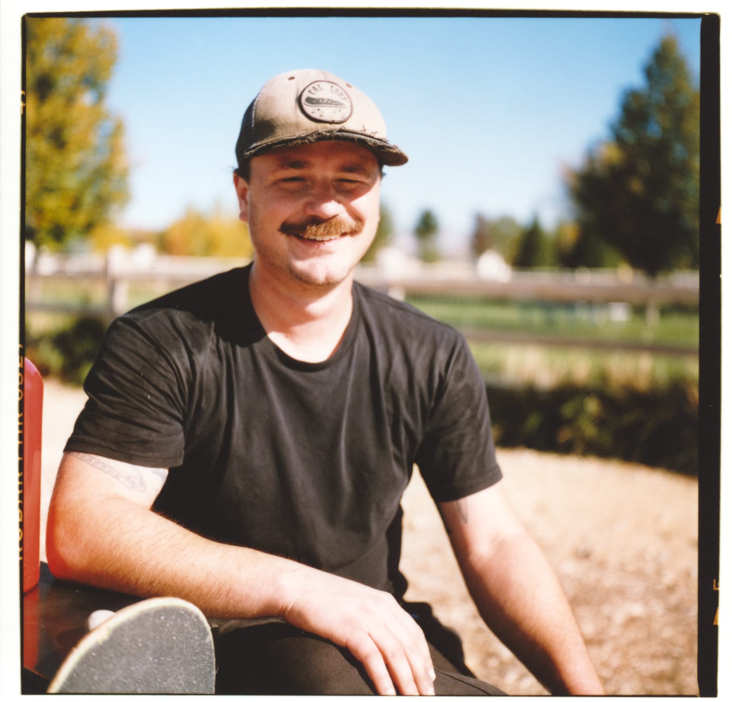Close up portrait of a a guy in a black t-shirt and faded hat.