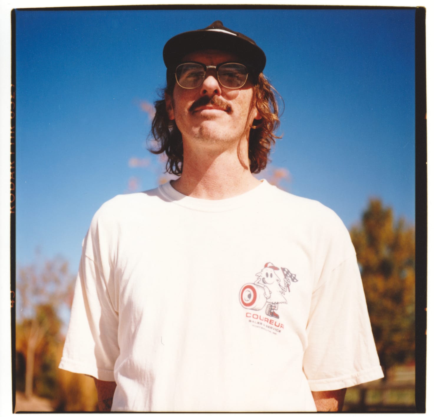 Close of portrait of a guy in a white shirt contrasted against a deep blue sky.